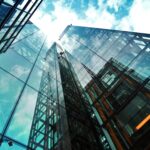 A striking view of a modern glass skyscraper reflecting the sky and clouds.